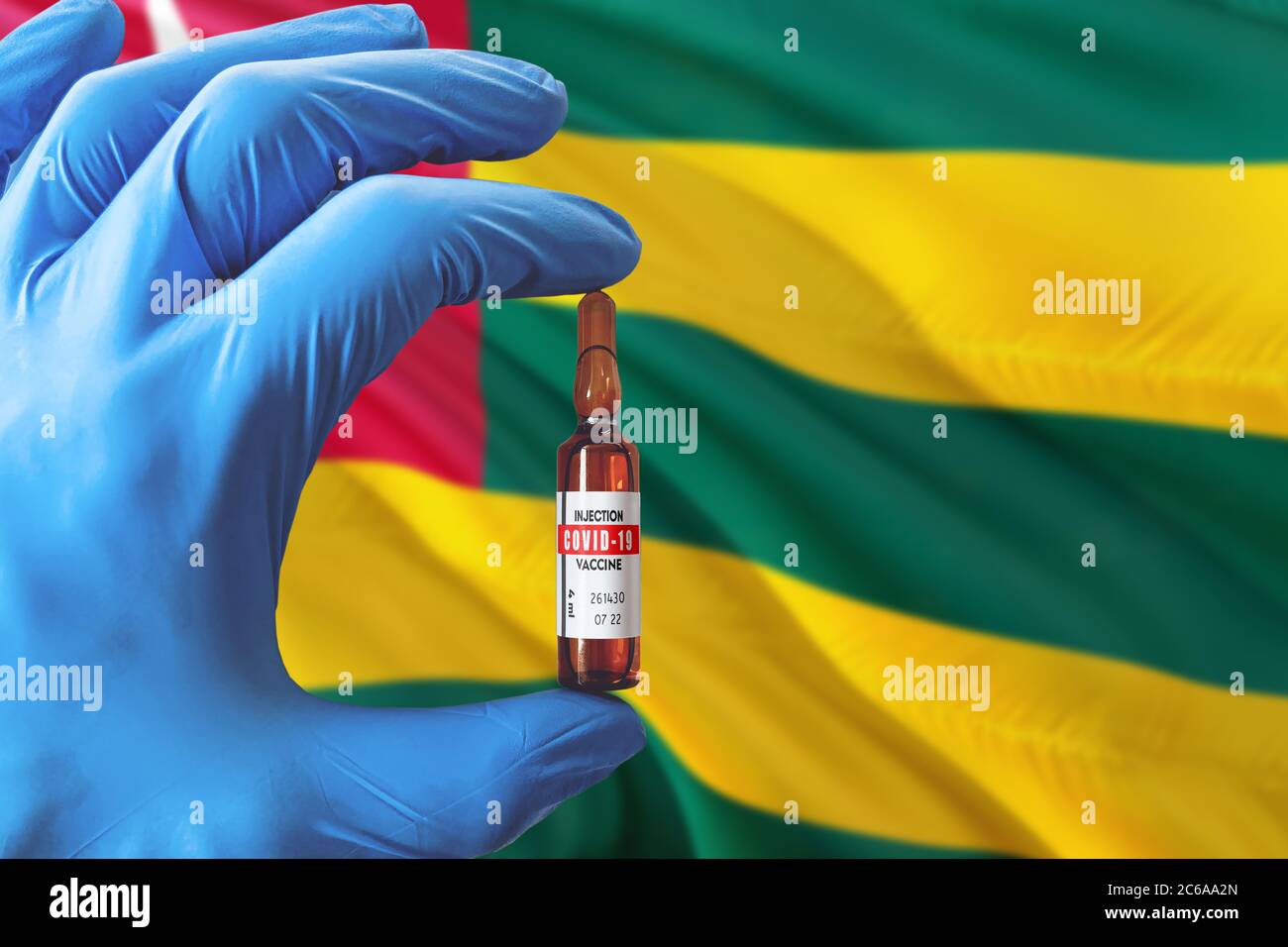 Togo Flagge mit Coronavirus Covid-19 Konzept. Arzt mit blauen Schutzhandschuhen mit einer Impfstoffflasche. Epidemic Virus, Cov-19, Corona Virus Stockfoto