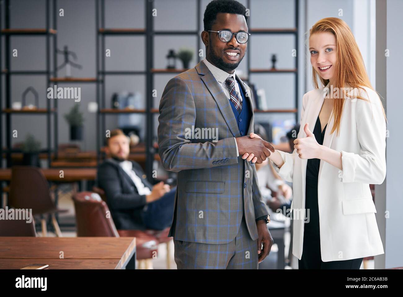 Verbundene Arbeit von zwei selbstbewussten Geschäftsleuten in formellen Anzug schüttelt Hände nach erfolgreicher Unterzeichnung des Vertrages.Moderne Business Meeting Office Hintergrund. Stockfoto