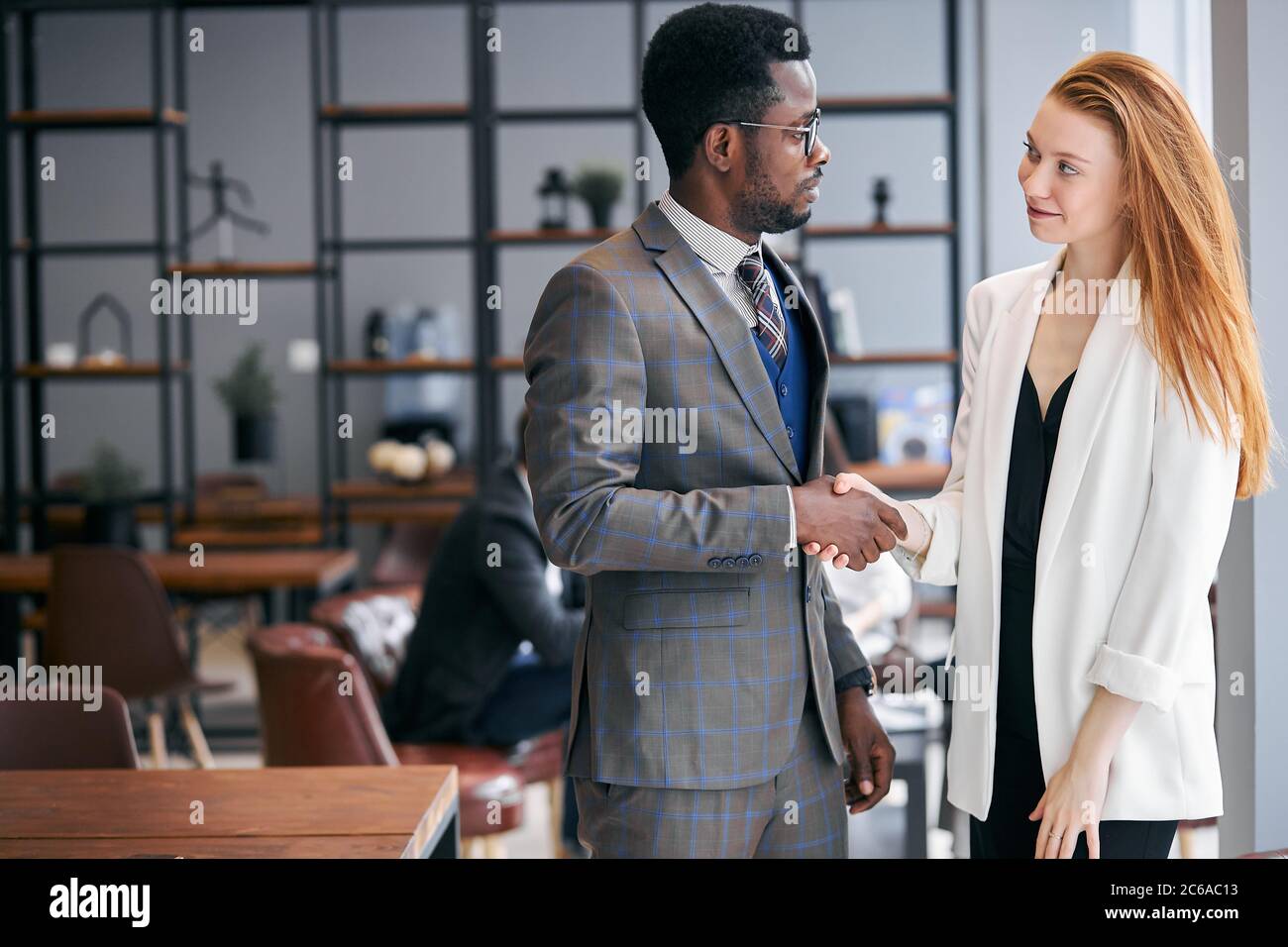 Verbundene Arbeit von zwei selbstbewussten Geschäftsleuten in formellen Anzug schüttelt Hände nach erfolgreicher Unterzeichnung des Vertrages.Moderne Business Meeting Office Hintergrund. Stockfoto