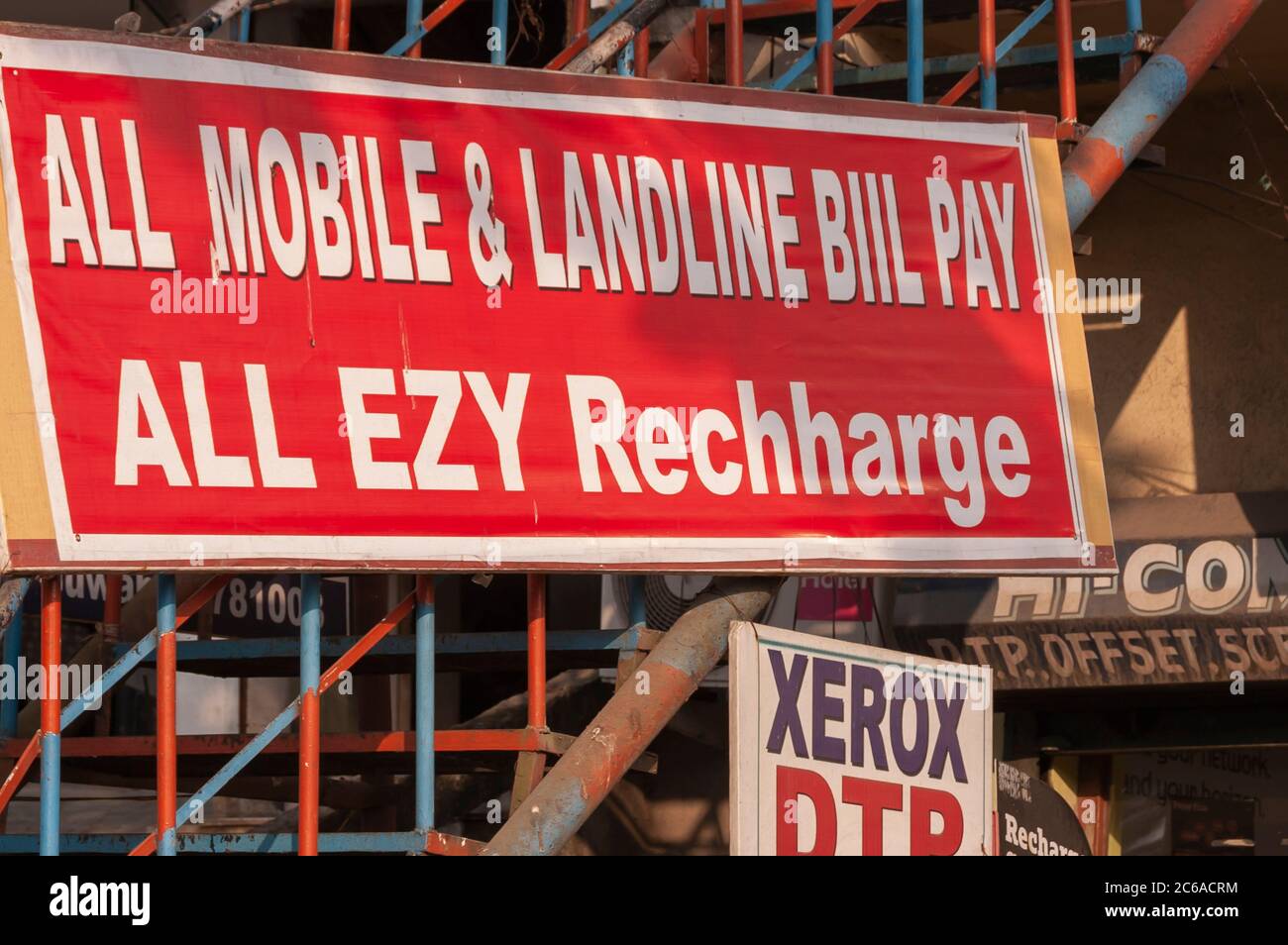 Eine Plakatwand/Hortung außerhalb eines Geschäftsbetriebs in Indien, die eine Handyladeeinrichtung anbietet. Das Wort 'Ladung' ist falsch geschrieben. Stockfoto