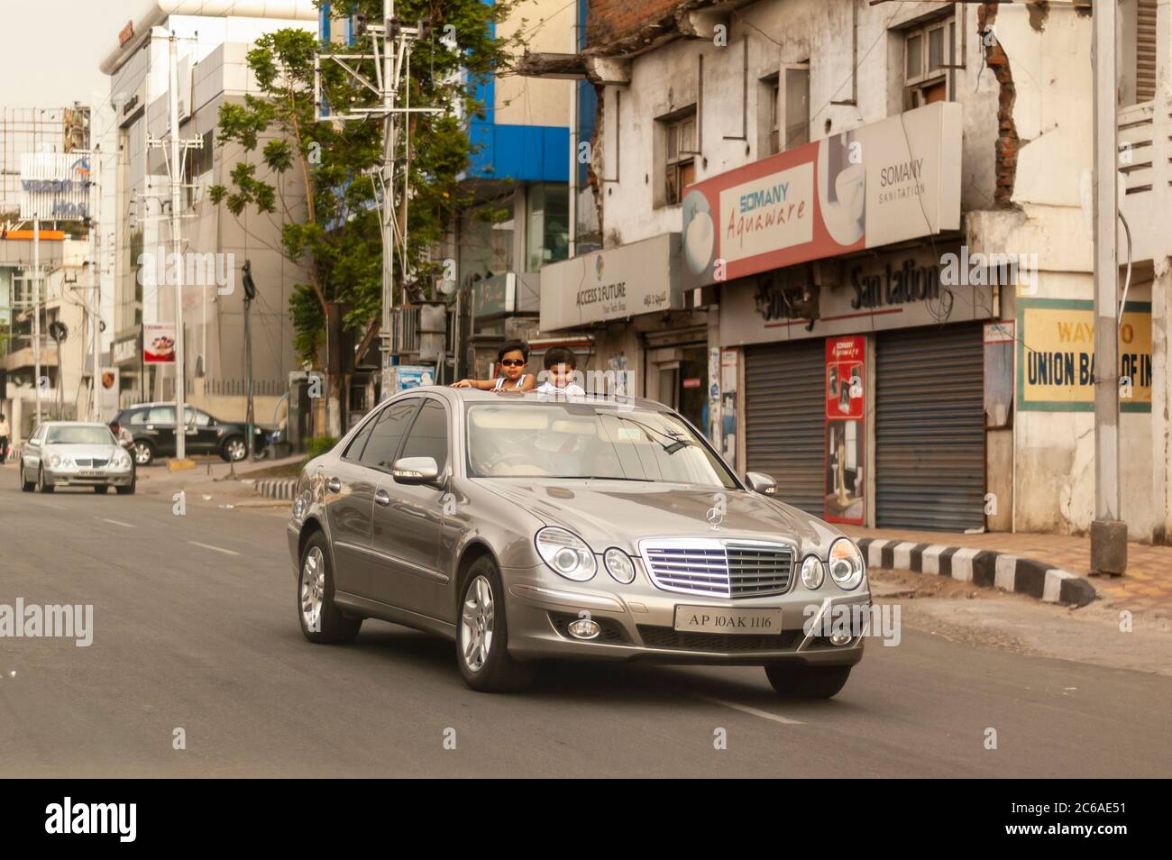 Ein Junge und ein Mädchen stehen auf dem Autositz, um durch das Schiebedach/Sonnendach/Sonnendach einer Mercedes-Benz Limousine zu stehen. Hyderabad, Telangana, Indien. Stockfoto