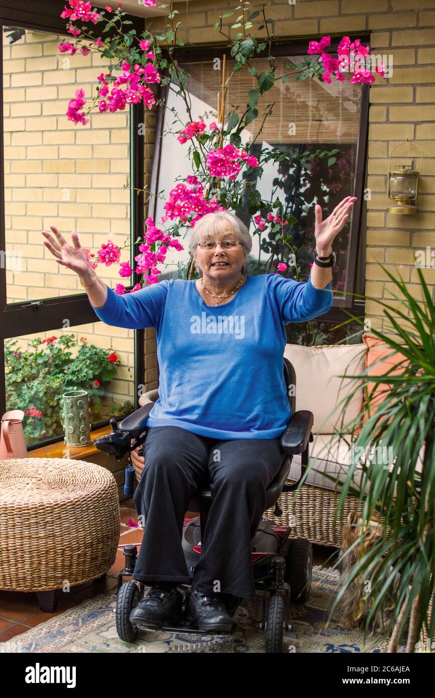 Ältere Frau im elektrischen Rollstuhl glücklich mit dem Leben Stockfoto