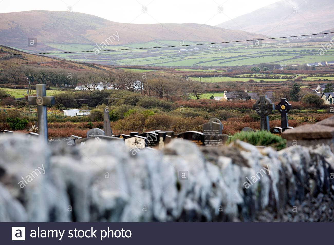 Eine Friedhofmauer und Grabsteine, wie sie an einem feuchten Tag von einer öffentlichen Straße in der West Kerry Gaeltacht in Irland fotografiert wurden. Stockfoto