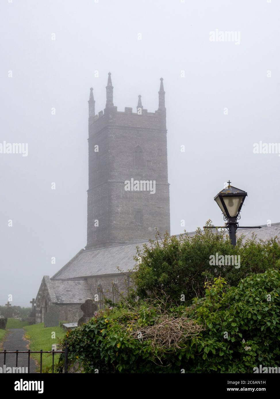 St Eval, Cornwall, Großbritannien. Juli 2020. Die Kirche von St. Eval ist in Nebel und Nebel gehüllt mitten in einem Sommertag, als trübe Wetter Teile von Südwestengland betroffen. Die Kirche aus dem 13. Jahrhundert befindet sich in einem stillgesetzten RAF-Flugplatz und ist bei unsaisonalem Wetter Teil einer stimmungsvollen Landschaft. Kredit: Julian Eales/Alamy Live Nachrichten Stockfoto