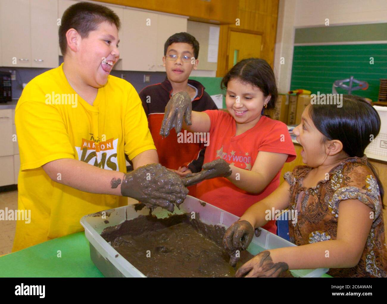 Austin, Texas, USA, 2005: Kinder, die nach der Schule an einem Programm teilnehmen, haben Spaß daran, sich die Hände schmutzig zu machen, während sie Ton für das Kunstprojekt herstellen. ©Bob Daemmrich Stockfoto