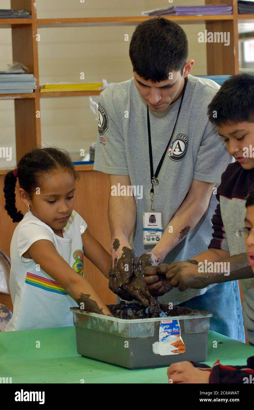 Austin, Texas, USA, 2005: Schüler und junge männliche Ausbilder im außerschulischen Programm haben Spaß dabei, sich die Hände schmutzig zu machen, während sie Ton für das Kunstprojekt herstellen. ©Bob Daemmrich Stockfoto