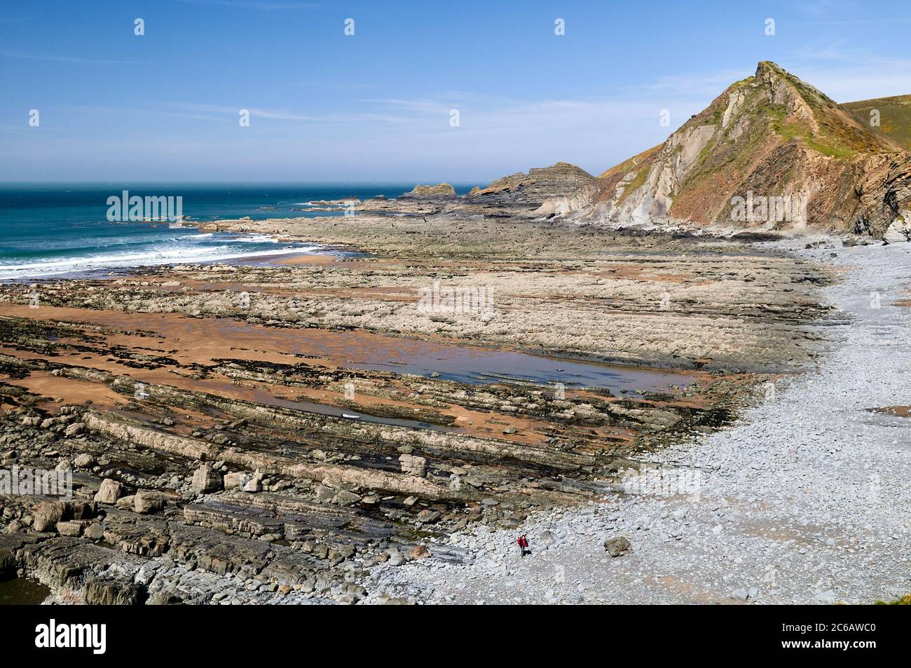 Einsamer Spaziergänger am Strand von Speke's Mill Mouth, North Devon, Großbritannien Stockfoto