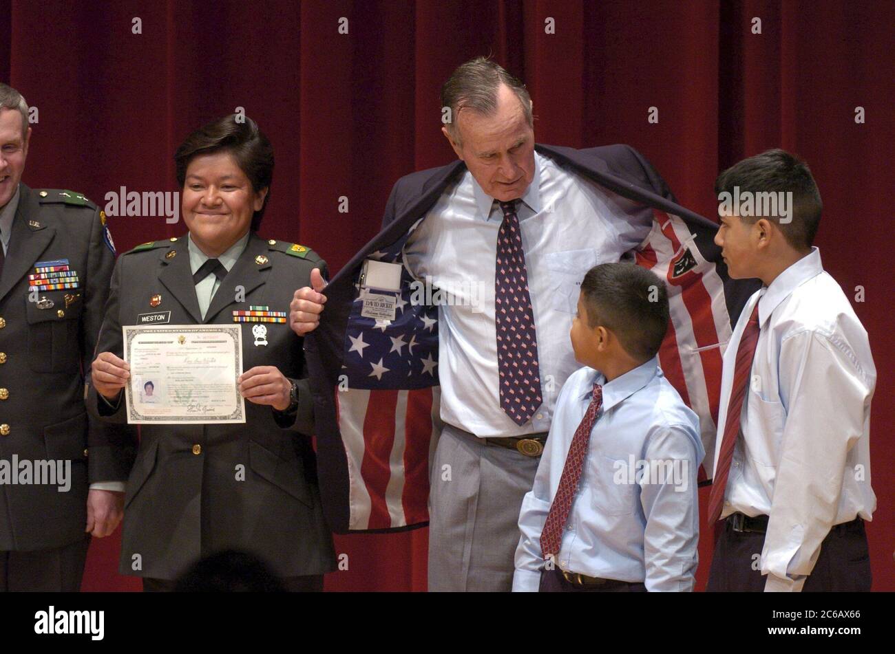 College Station, TX 11. März 2005: Der ehemalige US-Präsident George HW Bush (zweiter von links) zeigt Edward (9) und Alex (12) Weston als ihre Mutter Sgt vor seiner Sportküste mit einem amerikanischen Flaggenliner. Rosa Weston zeigt ihr Staatsbürgerschaftszertifikat bei Zeremonien Freitag an der Texas A&M University. ©Bob Daemmrich / Stockfoto