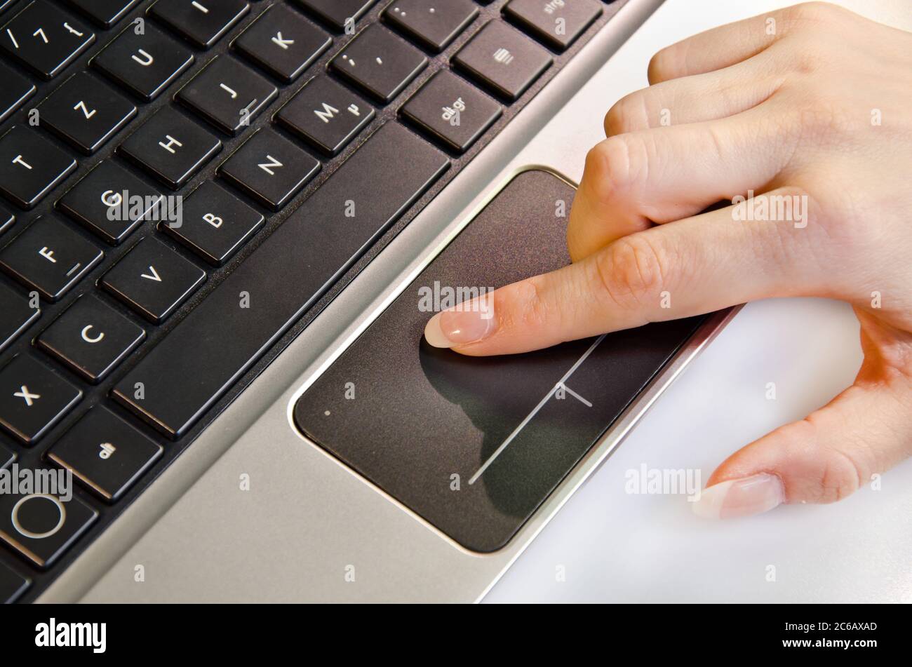 Weibliche Hand mit Trackpad auf einem Laptop Stockfoto