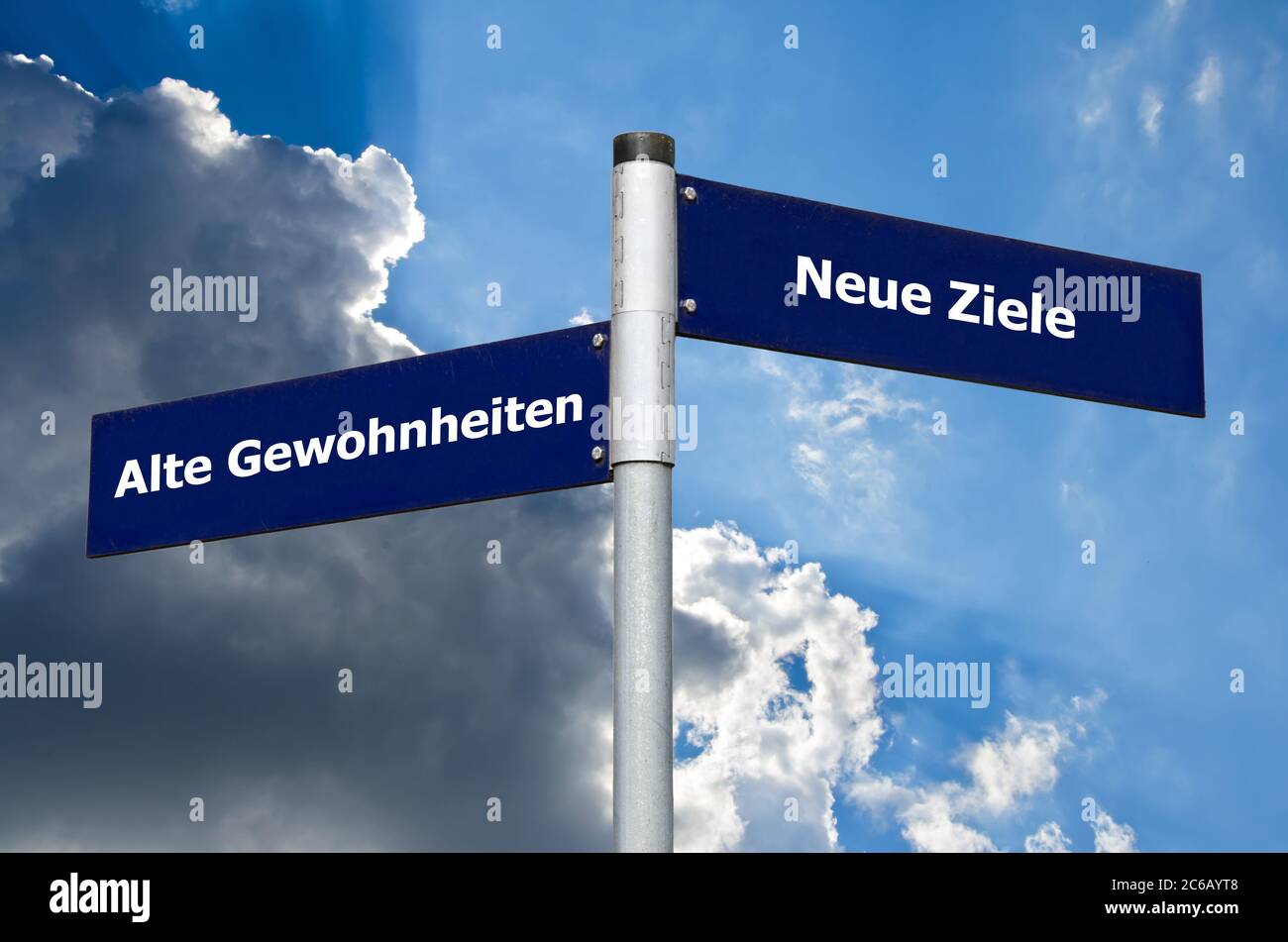 Straßenschild vor wolkenverhakter Luft, das die Wahl zwischen ‘Alten Gewöhnen’ und ‘Neuen Zielen’ auf Deutsch darstellt Stockfoto