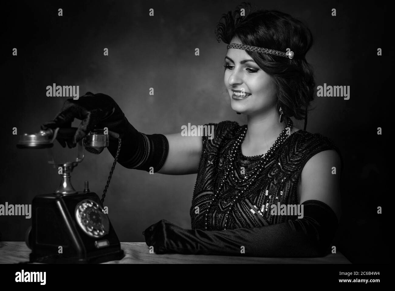 Elegante junge Frau in den 1920er Jahren nimmt das Telefon. Schwarz und Weiß Stockfoto