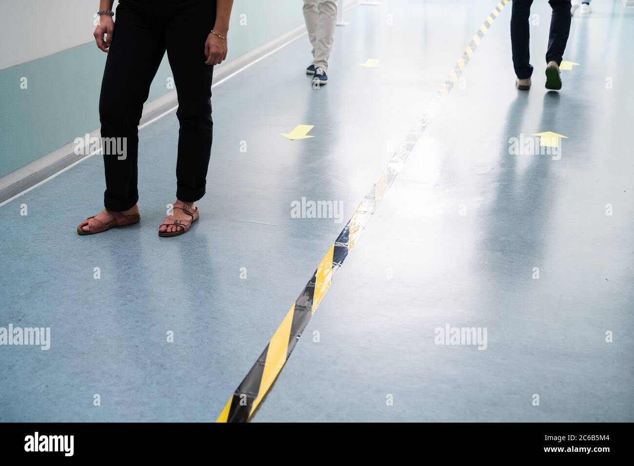 Mitarbeiter Im Büro Folgen Den Markierungen Des Social Distancing Tape Auf Dem Boden Stockfoto