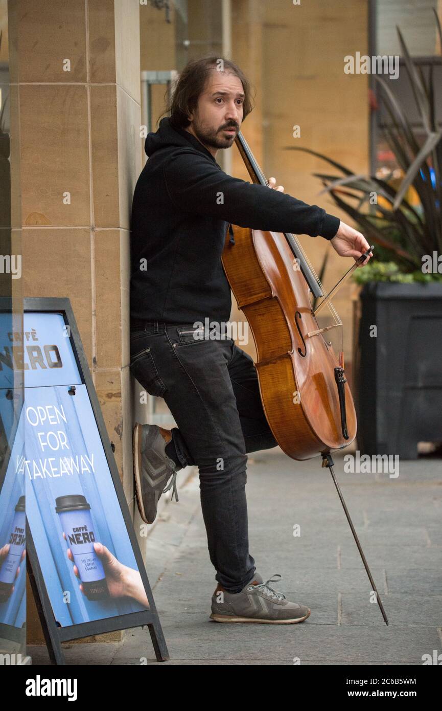 Glasgow, Schottland, Großbritannien. Juli 2020. Im Bild: Ein Musiker spielt an einem regnerischen Tag im Einkaufsviertel von Glasgow unter einem Vordach des Ladens klassische Hits auf seinem Cello. Quelle: Colin Fisher/Alamy Live News Stockfoto