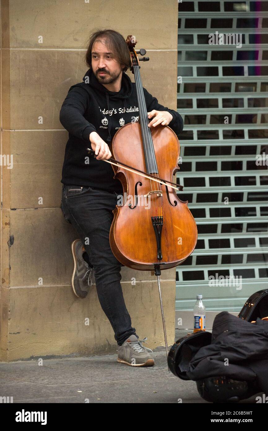 Glasgow, Schottland, Großbritannien. Juli 2020. Im Bild: Ein Musiker spielt an einem regnerischen Tag im Einkaufsviertel von Glasgow unter einem Vordach des Ladens klassische Hits auf seinem Cello. Quelle: Colin Fisher/Alamy Live News Stockfoto