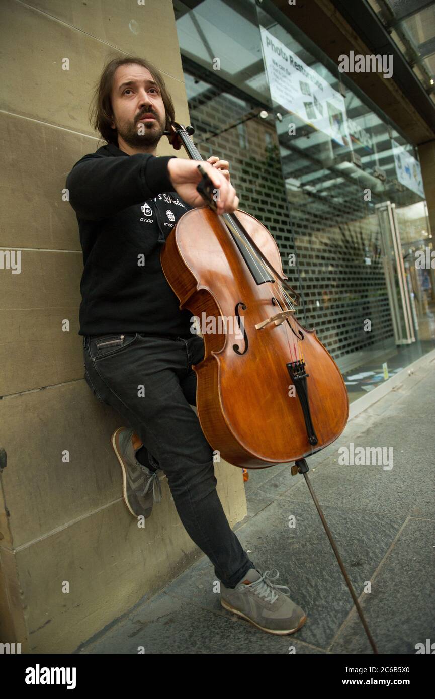 Glasgow, Schottland, Großbritannien. Juli 2020. Im Bild: Ein Musiker spielt an einem regnerischen Tag im Einkaufsviertel von Glasgow unter einem Vordach des Ladens klassische Hits auf seinem Cello. Quelle: Colin Fisher/Alamy Live News Stockfoto