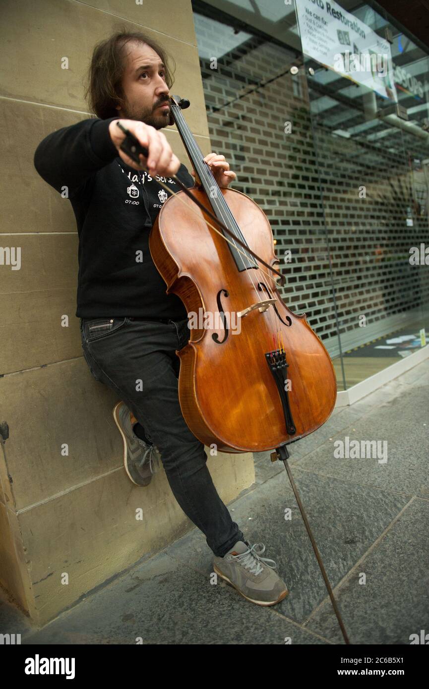 Glasgow, Schottland, Großbritannien. Juli 2020. Im Bild: Ein Musiker spielt an einem regnerischen Tag im Einkaufsviertel von Glasgow unter einem Vordach des Ladens klassische Hits auf seinem Cello. Quelle: Colin Fisher/Alamy Live News Stockfoto