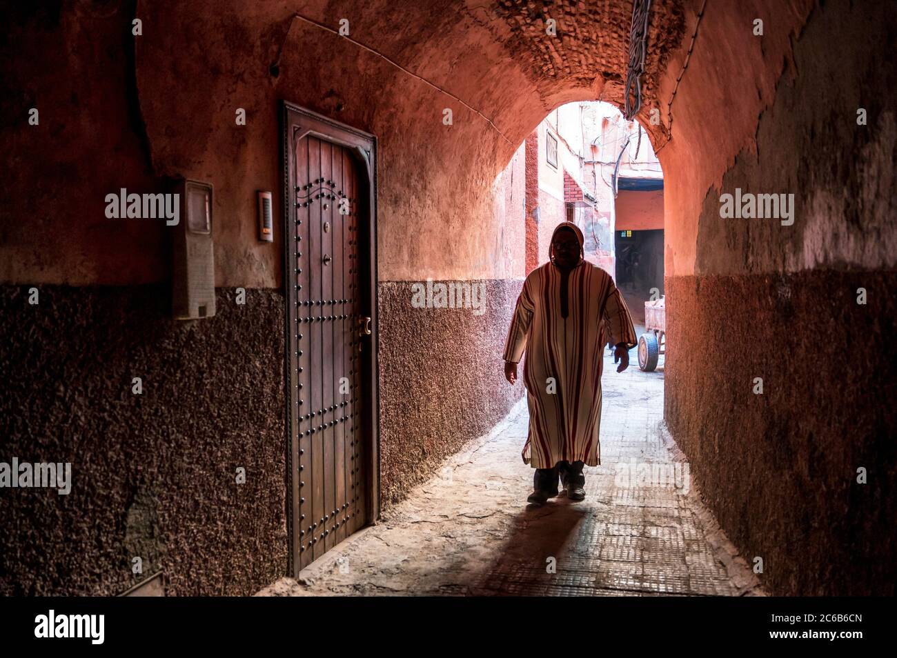 Lokaler Mann in traditionellen djellaba gekleidet zu Fuß durch Torbogen in einer Straße in der Kasbah, Marrakesch, Marokko, Nordafrika, Afrika Stockfoto