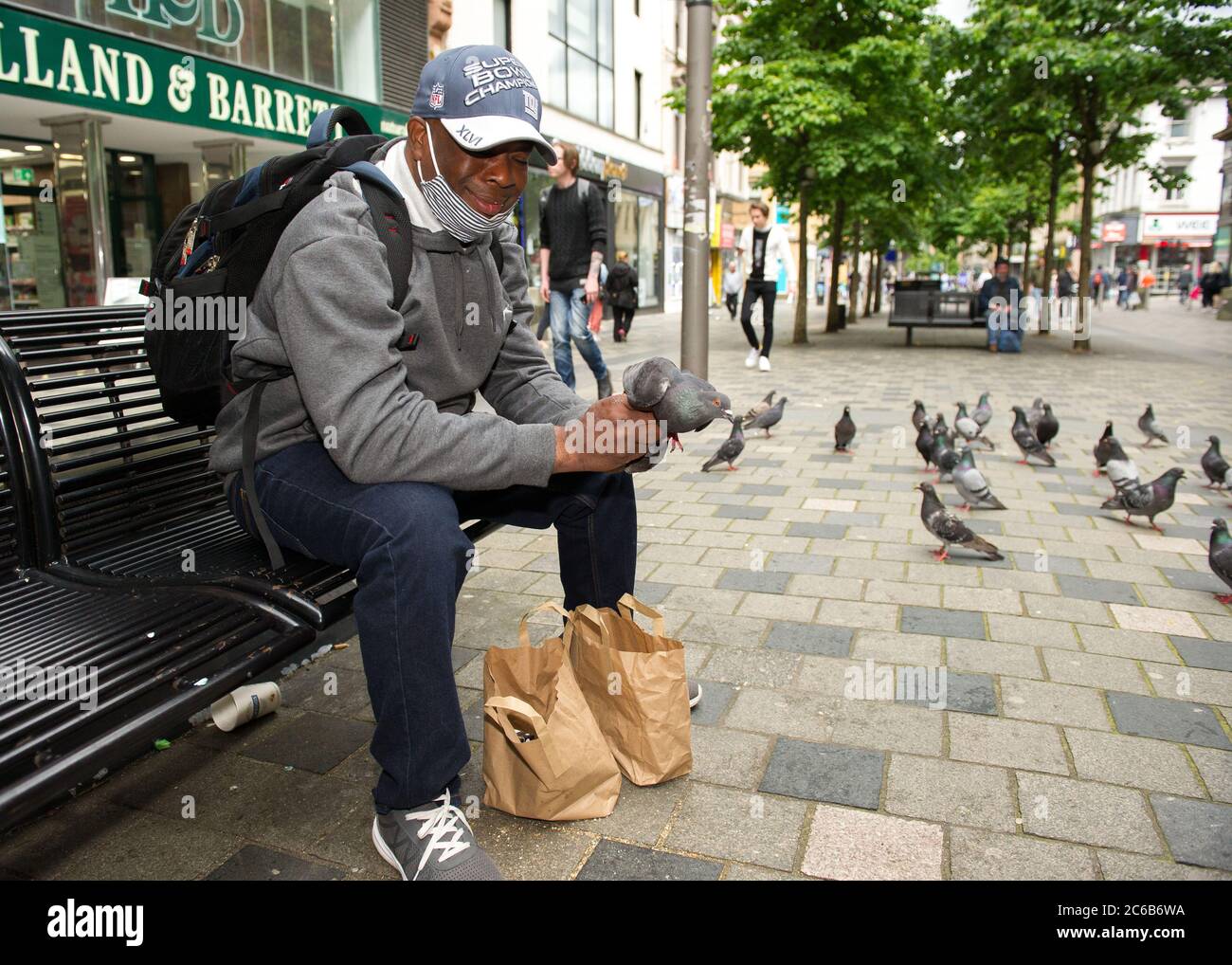 Glasgow, Schottland, Großbritannien. Juli 2020. Im Bild: Ein Mann füttert Tauben von Hand in der Sauchielhall Straße im Glasgows Einkaufsviertel. Quelle: Colin Fisher/Alamy Live News Stockfoto