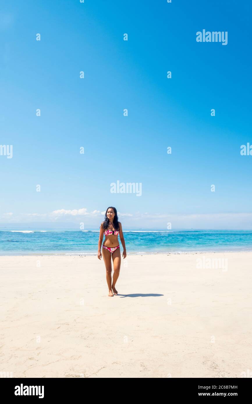 Eine schöne asiatische Frau allein Reisende in einem Bikini an einem unberührten tropischen Strand, Bali, Indonesien, Südostasien, Asien Stockfoto
