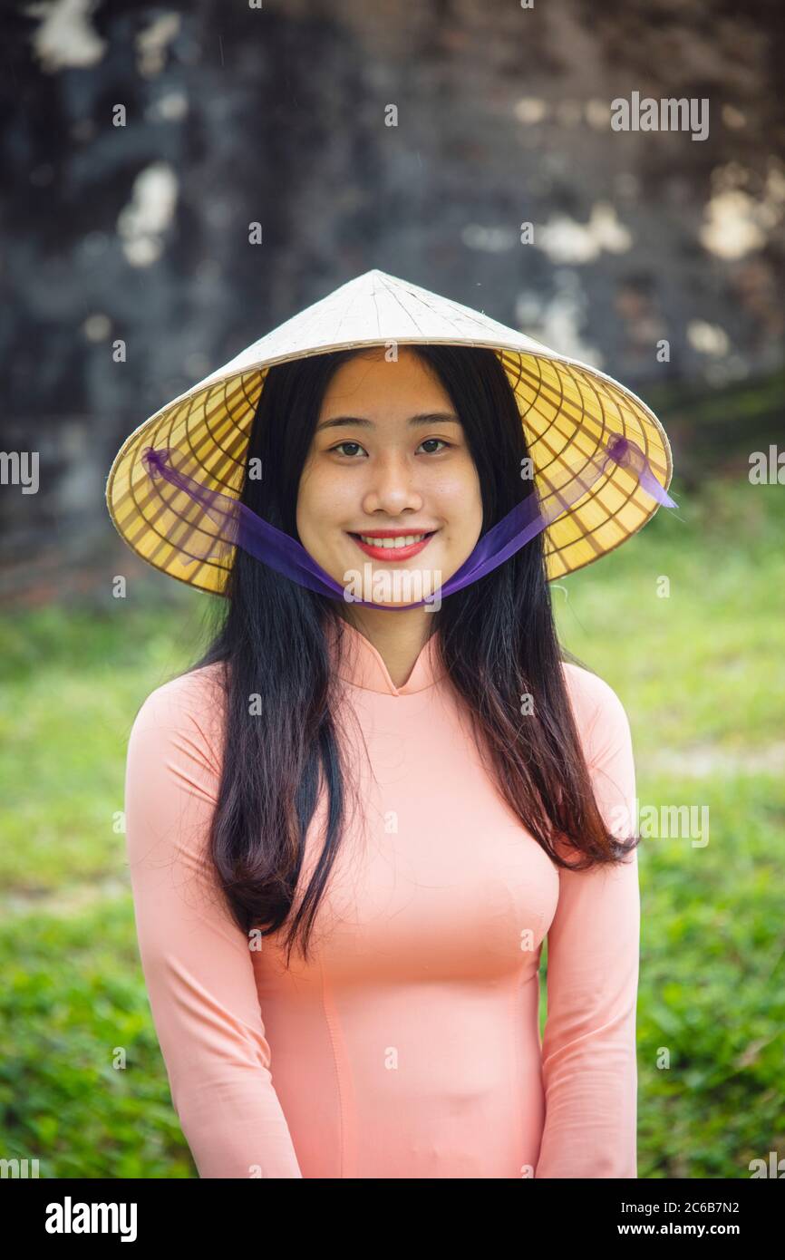 Eine junge Vietnamesin in einem traditionellen Ao Dai Kleid und konischen Hut und lächelnd, Hue, Vietnam, Indochina, Südostasien, Asien Stockfoto