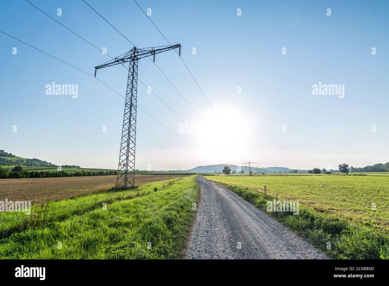 Feldweg neben Stromleitungen in ländlicher Landschaft Stockfoto