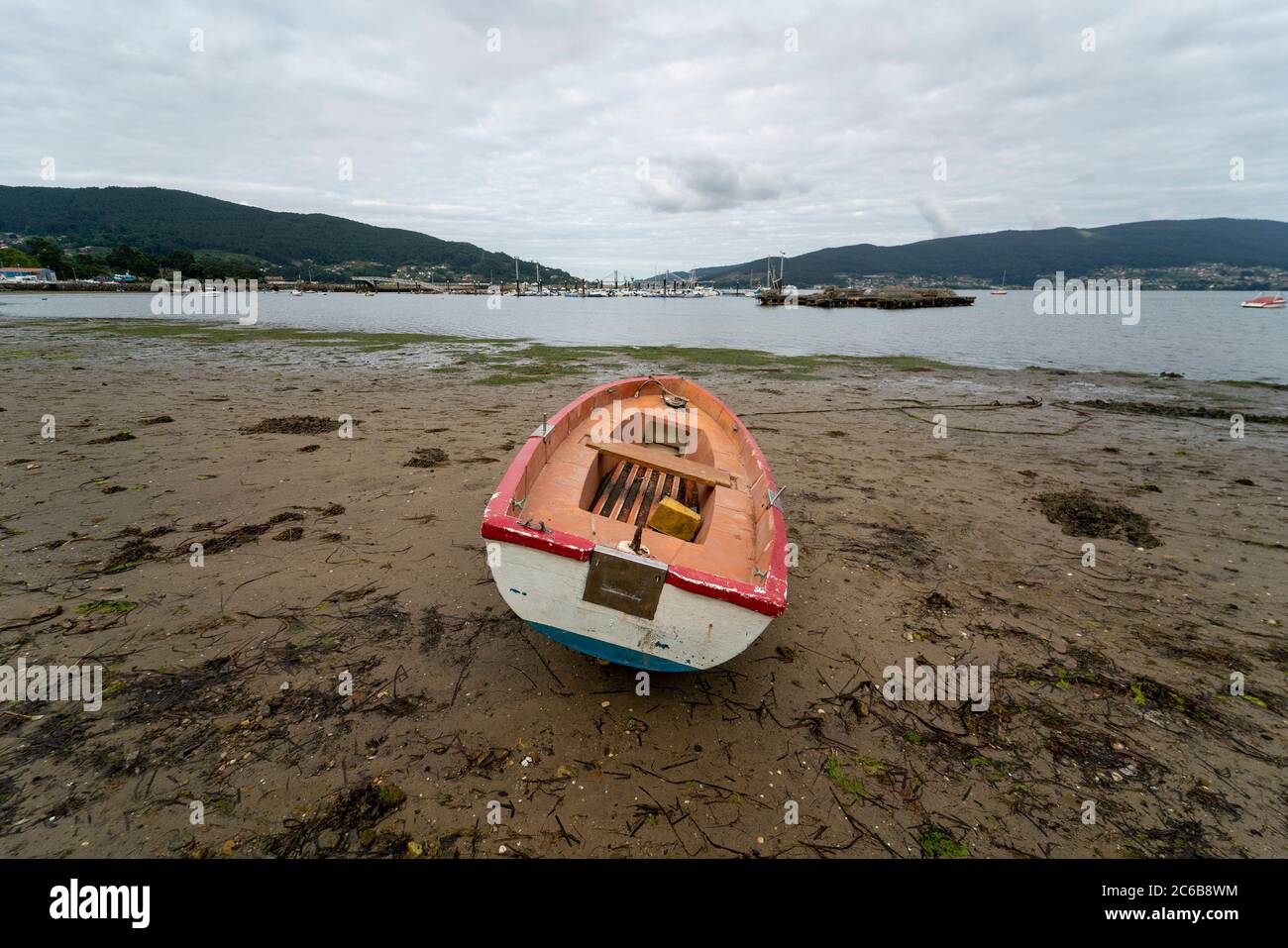 Kleines hölzernes Ruderboot, das auf einem Strand in niedrig gestrandet ist Gezeiten Stockfoto