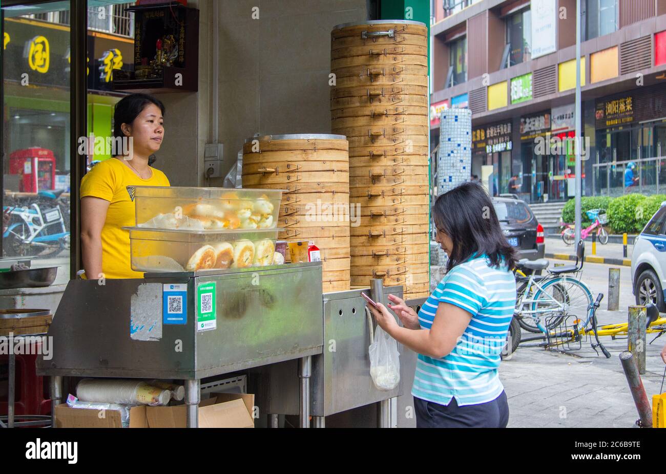 Shenzhen, China - November 14 2018: Eine Kundin zahlt mit dem Smartphone den jer-Frühstückskauf an einem Straßenstand mit QR-Code. Digitaliz Stockfoto