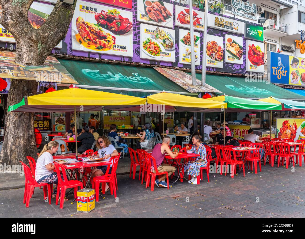 Menschen, die vor einem lokalen Restaurant auf Jalan Alor sitzen, einer Straße im Goldenen Dreieck, die für ihr Essen und Trinken berühmt ist, Kuala Lumpur, Malaysia Stockfoto