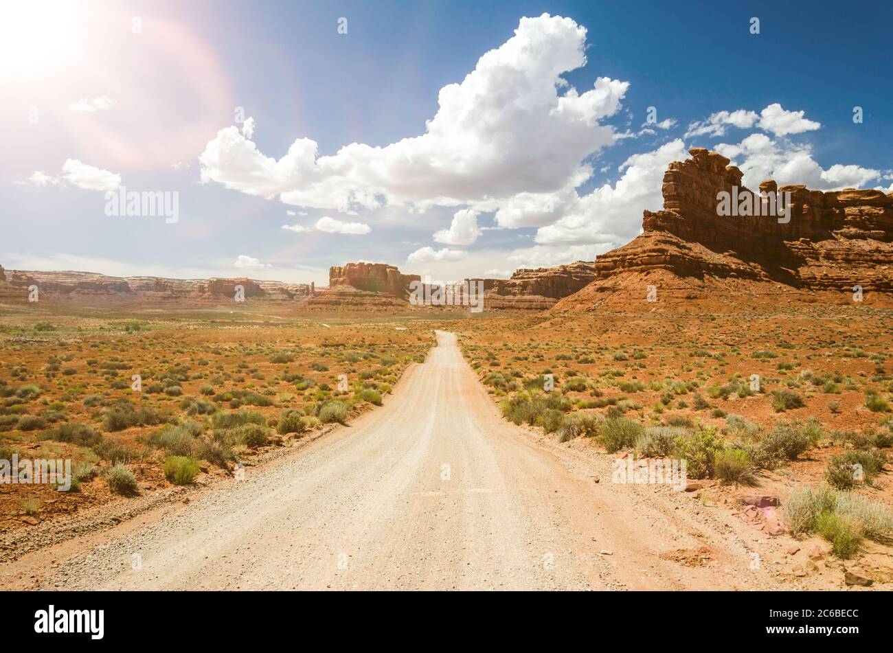 Dirt Road in der Wüste mit roten Felsen im Hintergrund und landschaftlich schönen Lichtreflexen Stockfoto