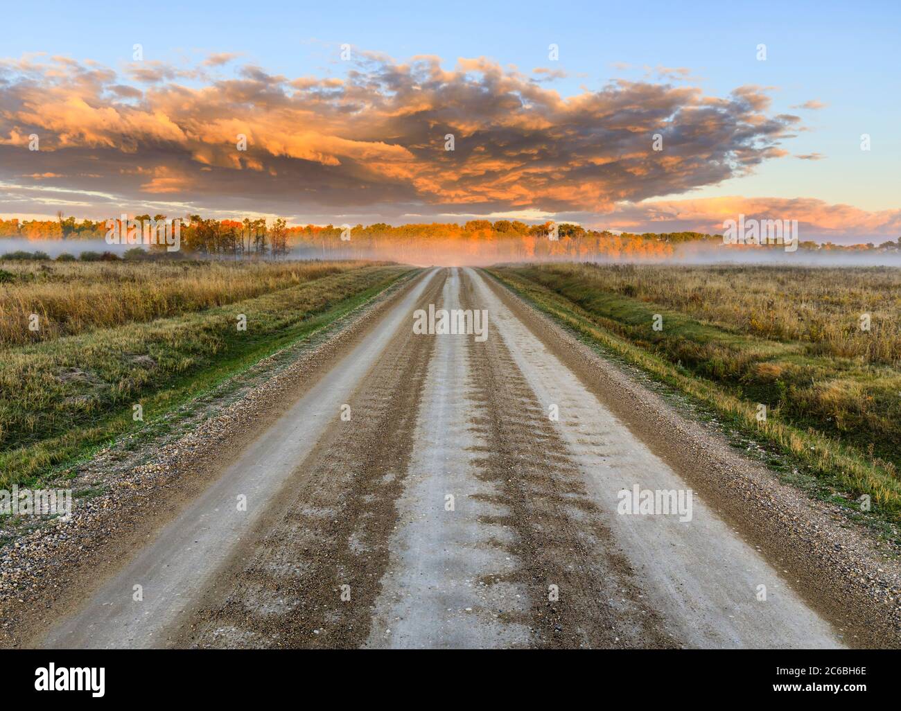 Eine Feldstraße bei Sonnenaufgang, Western Manitoba, Kanada. Stockfoto