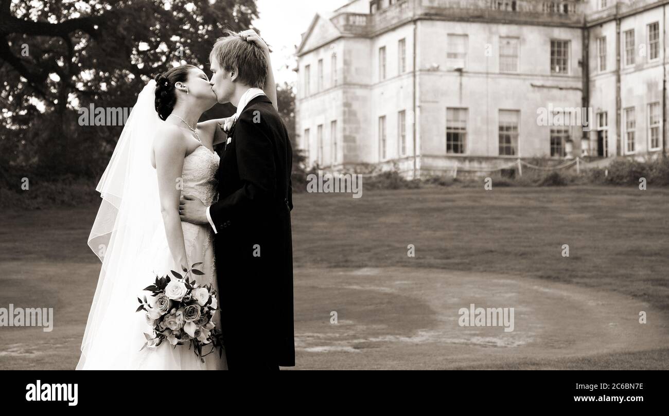 Sepia Braut & Bräutigam Paar in ihren Zwanzigern küssen leidenschaftlich an ihrem Hochzeitstag in Addington Palace Villa Veranstaltungsort. Stockfoto