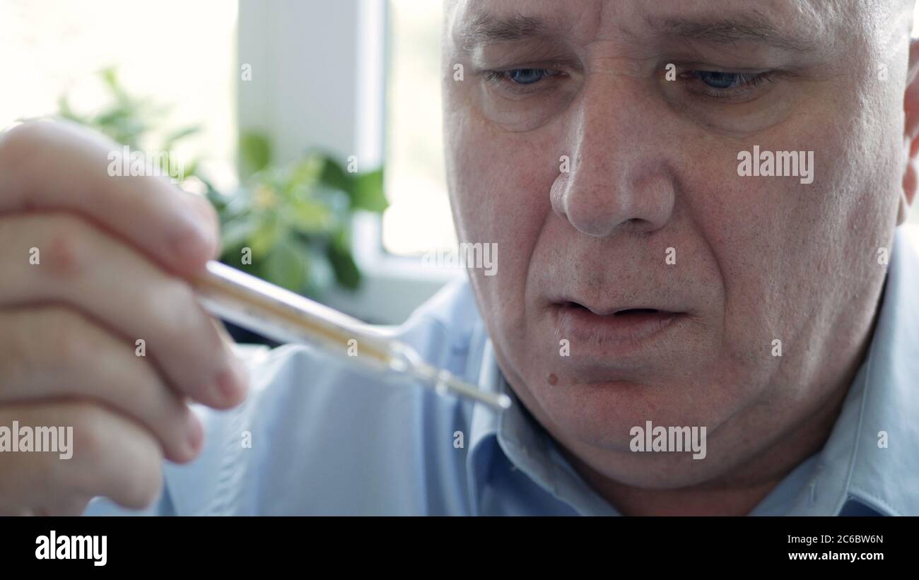 Mann mit Coronavirus-Symptomen, der seine Körpertemperatur in einem Krankenhaus mit einem Thermometer mit Quecksilberskala einnahm Stockfoto