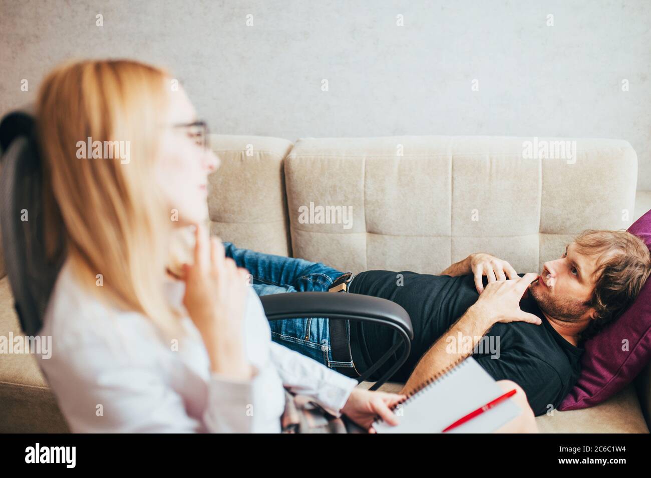 Kaukasischer männlicher Patient liegt auf einer Couch in einem Psychologiebüro - psychologische Beratung - Behandlung für Alkoholismus und Drogenabhängigkeit Stockfoto
