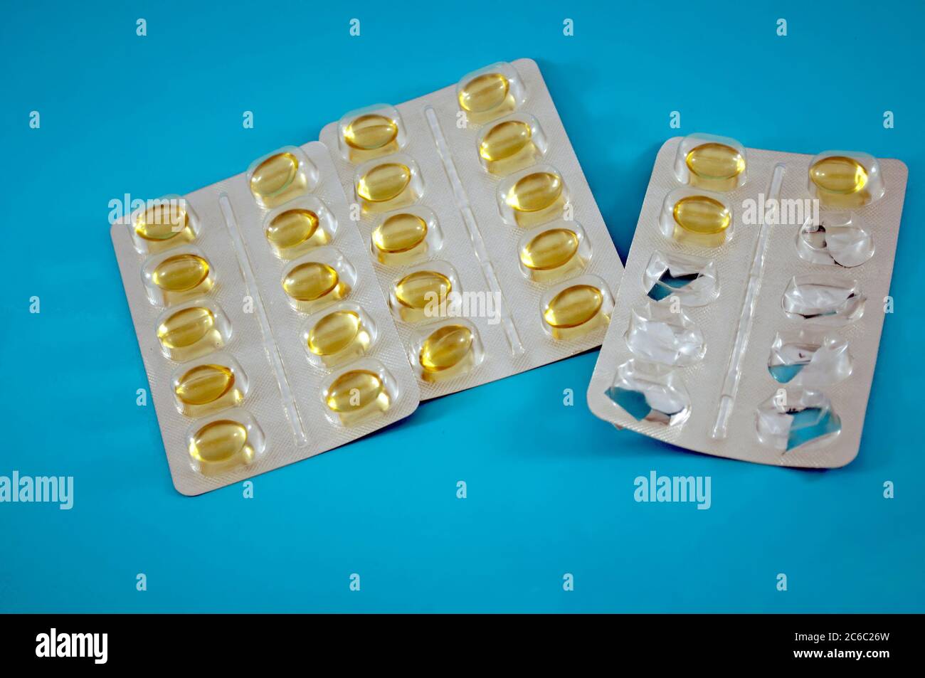 Blister von gelben Pillen, Vitamine, Tablette, Medizin auf blauem Hintergrund Stockfoto