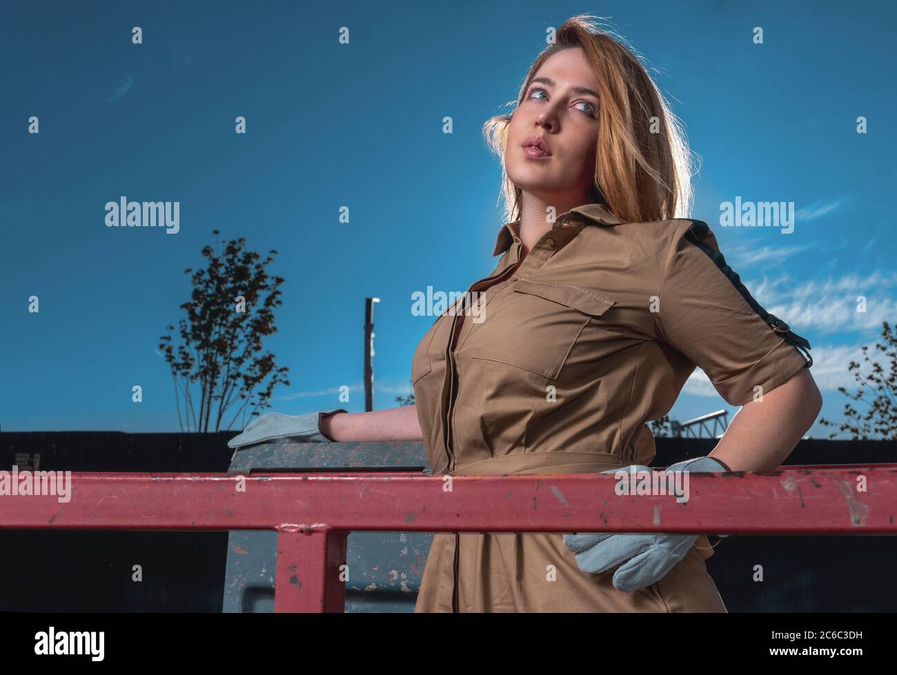 Schöne glamouröse Frau in stilvollen Kleid und Arbeiter Handschuhe an Construction Cradle Stockfoto