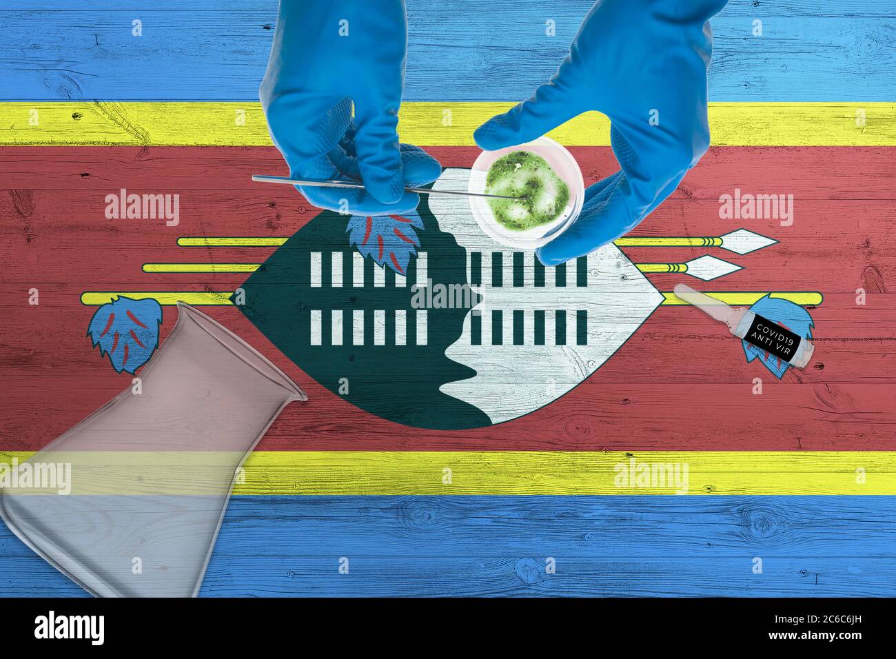 Swasiland-Flagge auf dem Labortisch. Medizinischer Techniker mit COVID-19-Abstrichbesteck, blaue Schutzhandschuhe, epidemische Kontra Stockfoto