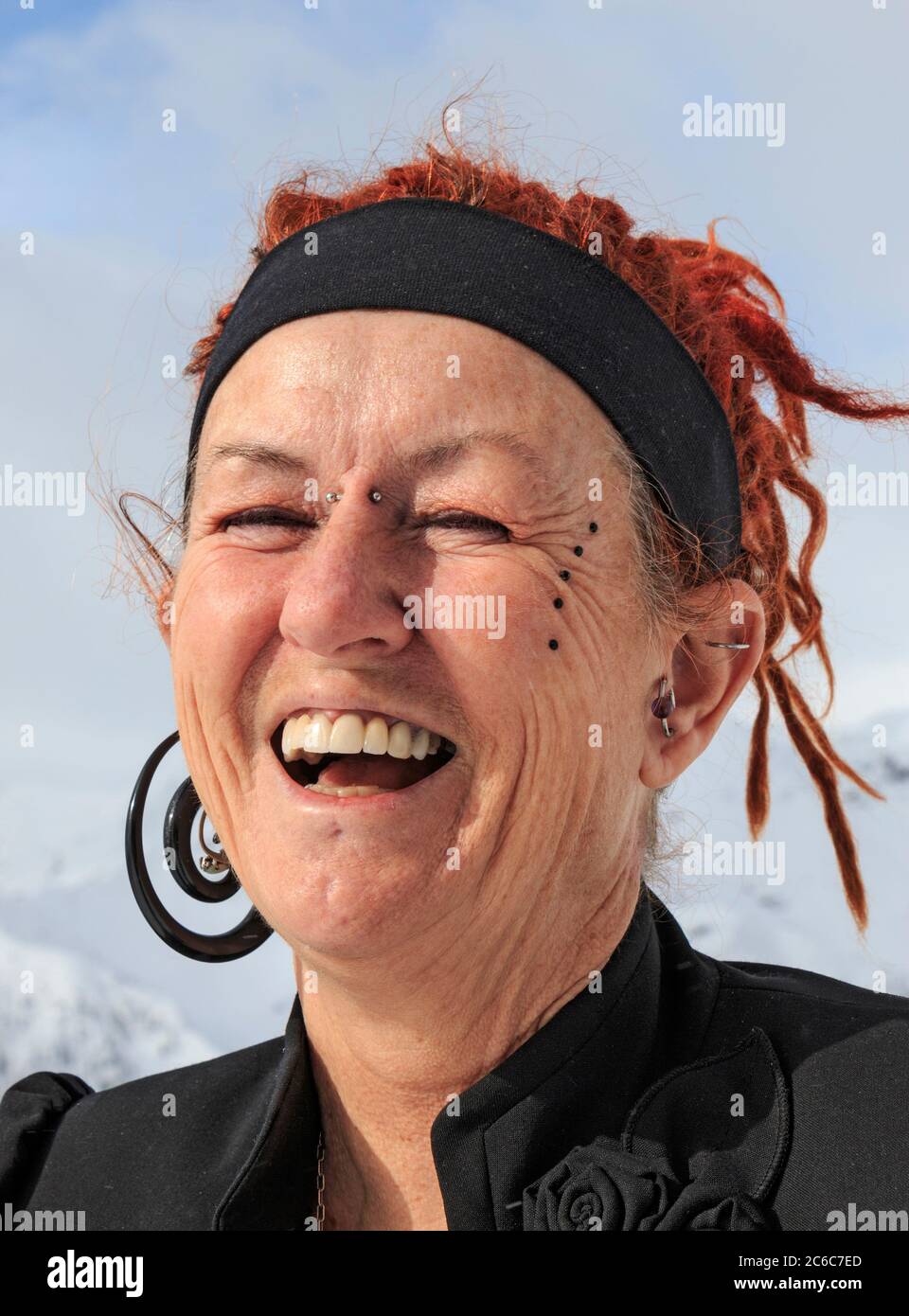 Frau mit interessanten Haaren, Tattoos und Piercings im Winter mit einem verschneiten Hintergrund. Stockfoto