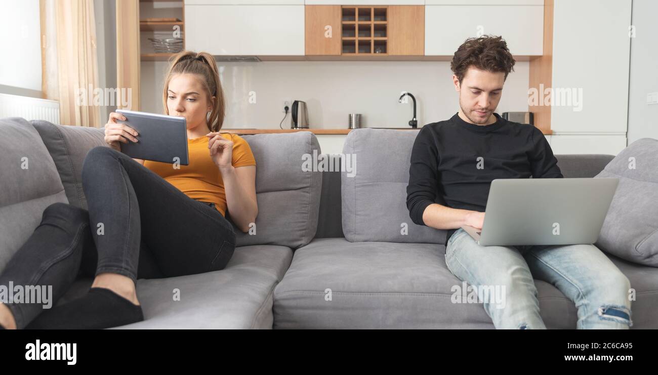 Krise in Partnerschaft, Trennung, Internetsucht. Paar getrennt auf Sofa im Wohnzimmer Stockfoto