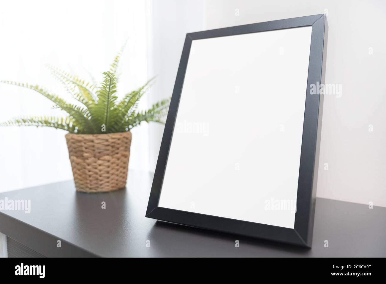 Nahaufnahme eines leeren Fotorahmens im Wohnzimmer. Schwarze rechteckige Mockup-Rahmen für Ihre Präsentation oder Foto. Stockfoto