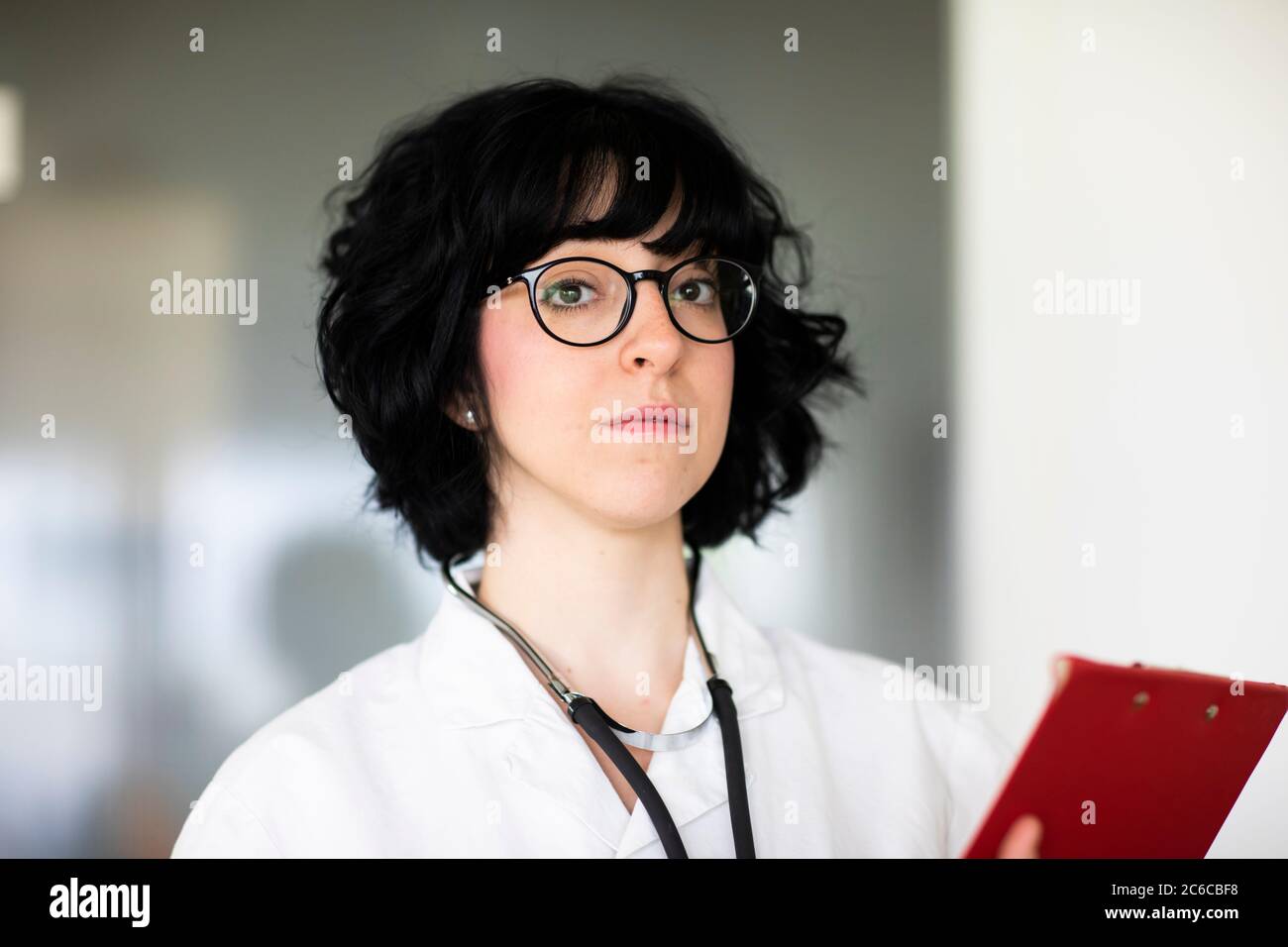 Junge Ärztin mit weißem Mantel Stockfoto