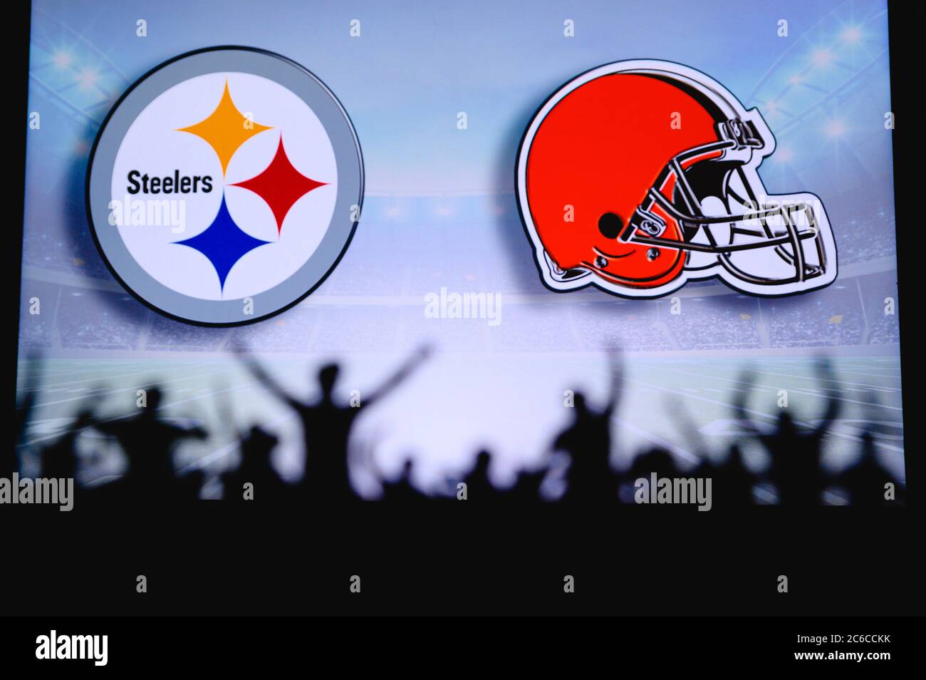 Pittsburgh Steelers vs. Cleveland Browns. Fans unterstützen NFL Game. Silhouette der Unterstützer, große Leinwand mit zwei Rivalen im Hintergrund. Stockfoto