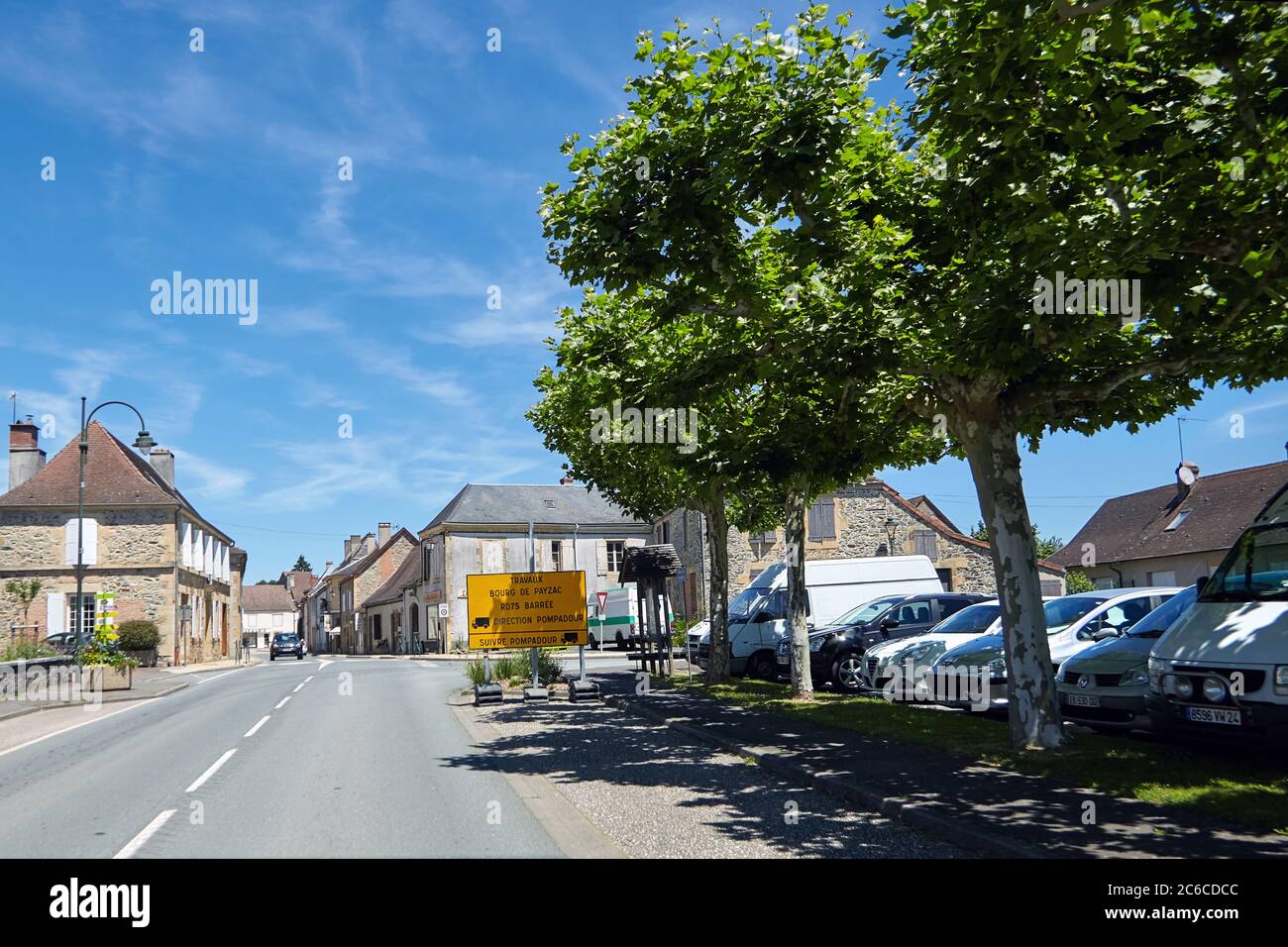 Lanouaille, Departement Dordogne, Region Nouvelle-Aquitaine, Frankreich - 23. Juni 2018: Rue du Perigord. Geparkte Autos entlang der Landstraße D704 passieren Stockfoto