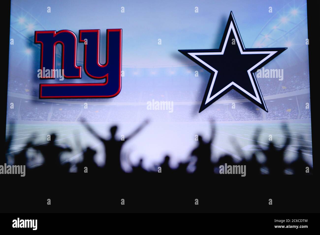 New York Giants gegen Dallas Cowboys. Fans unterstützen NFL Game. Silhouette der Unterstützer, große Leinwand mit zwei Rivalen im Hintergrund. Stockfoto