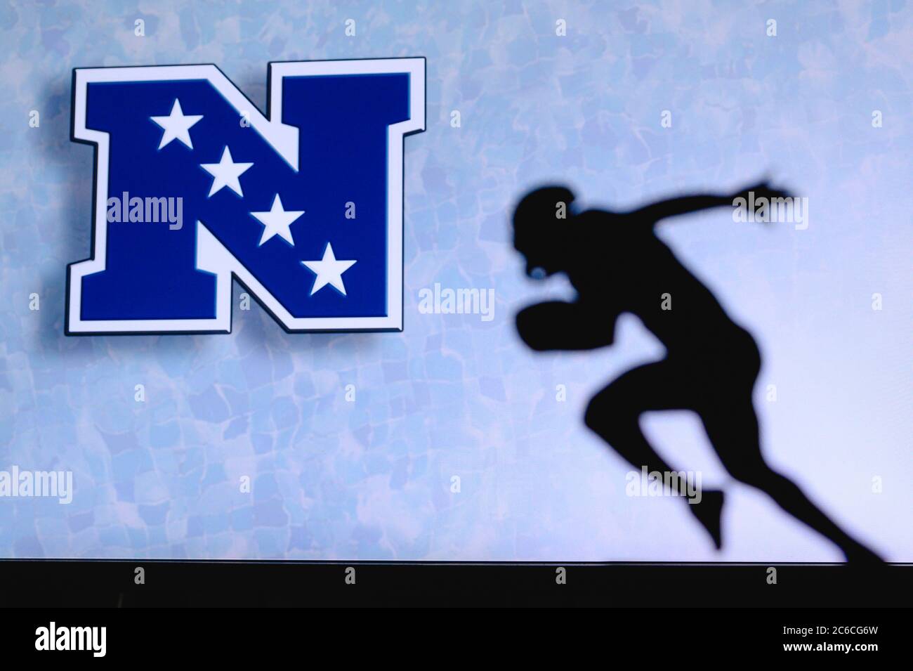 Nationale Fußballkonferenz – NFC, . Silhouette des professionellen amerikanischen Fußballspielers. Logo des NFL-Clubs im Hintergrund, bearbeiten Raum. Stockfoto