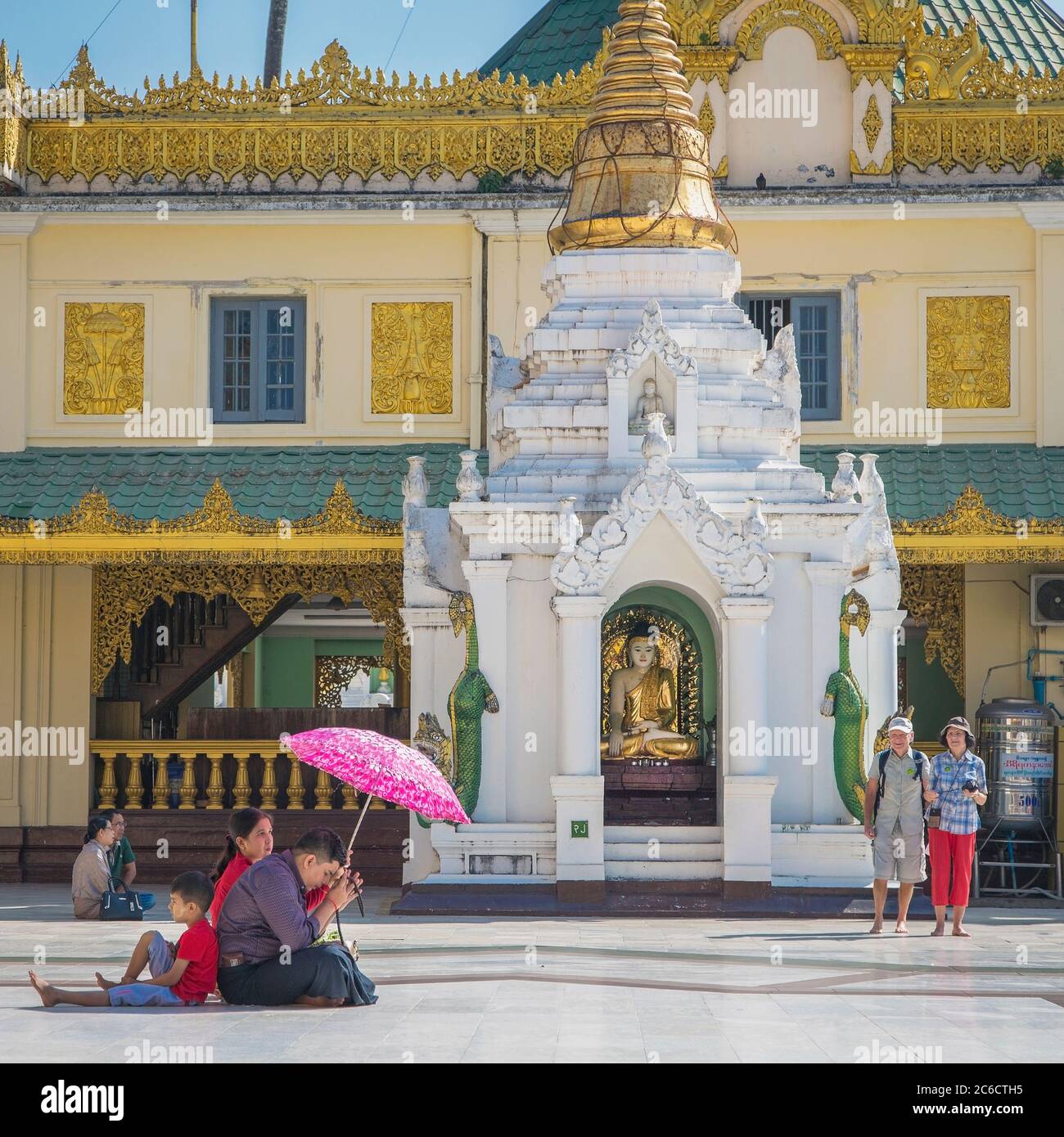 Eine junge Familie betet an einem Schrein zu Buddha in der Shwedagon Pagode in Yangon, Myanmar Stockfoto