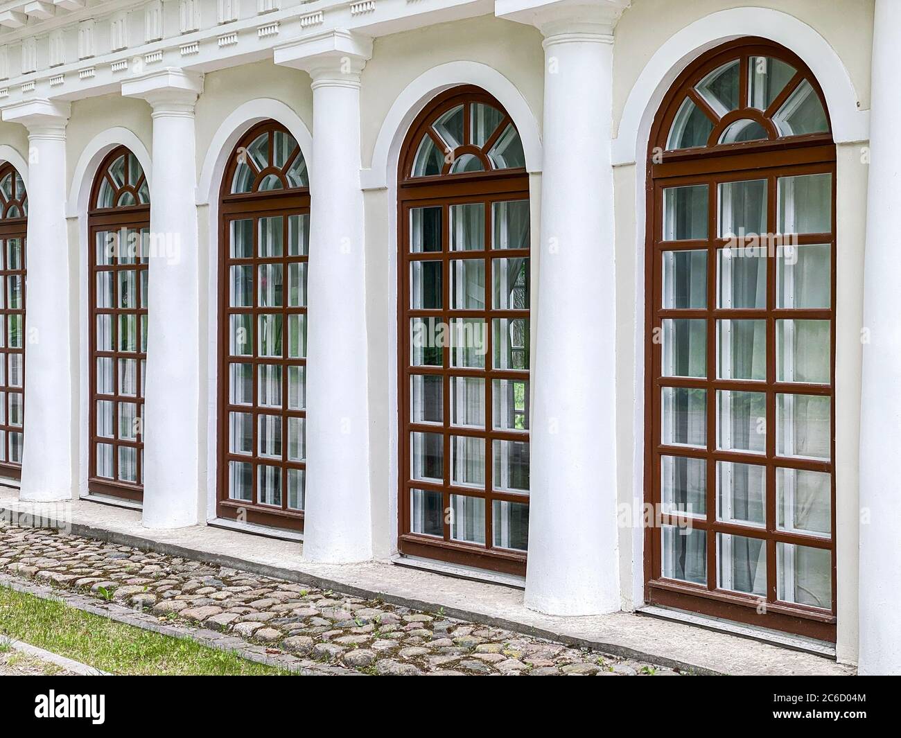Vintage-Gebäudefassade mit gewölbten französischen Fenstern und Säulen. Klassische europäische Architektur. Stockfoto