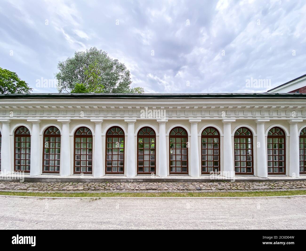 Klassische Fassade eines Vintage-Gebäudes mit einer Reihe großer, bogenförmig anbauter französischer Fenster vor dramatischem, wolkigen Hintergrund Stockfoto