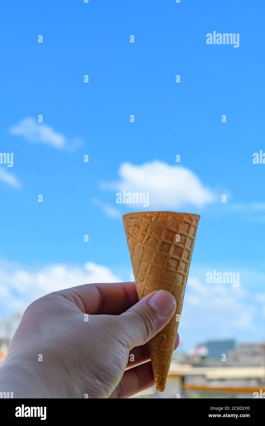 Hand hält einen Kegel unter Wolke wie ein Eis-Kegel geformt Stockfoto