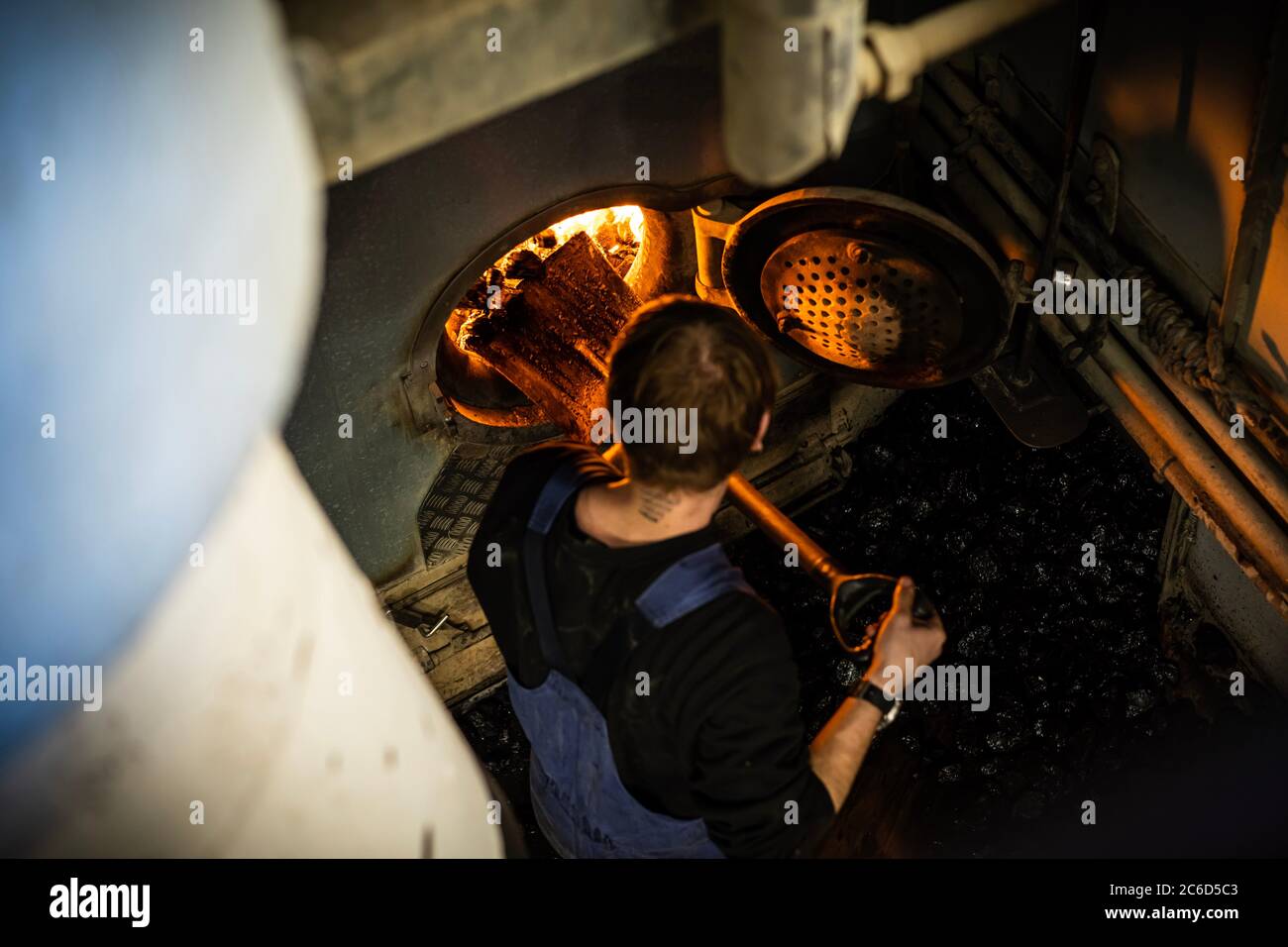 Ein Arbeiter fügt eine Kohle in den Motor des Dampfschiffs mit gecoaled Kraft ein Stockfoto