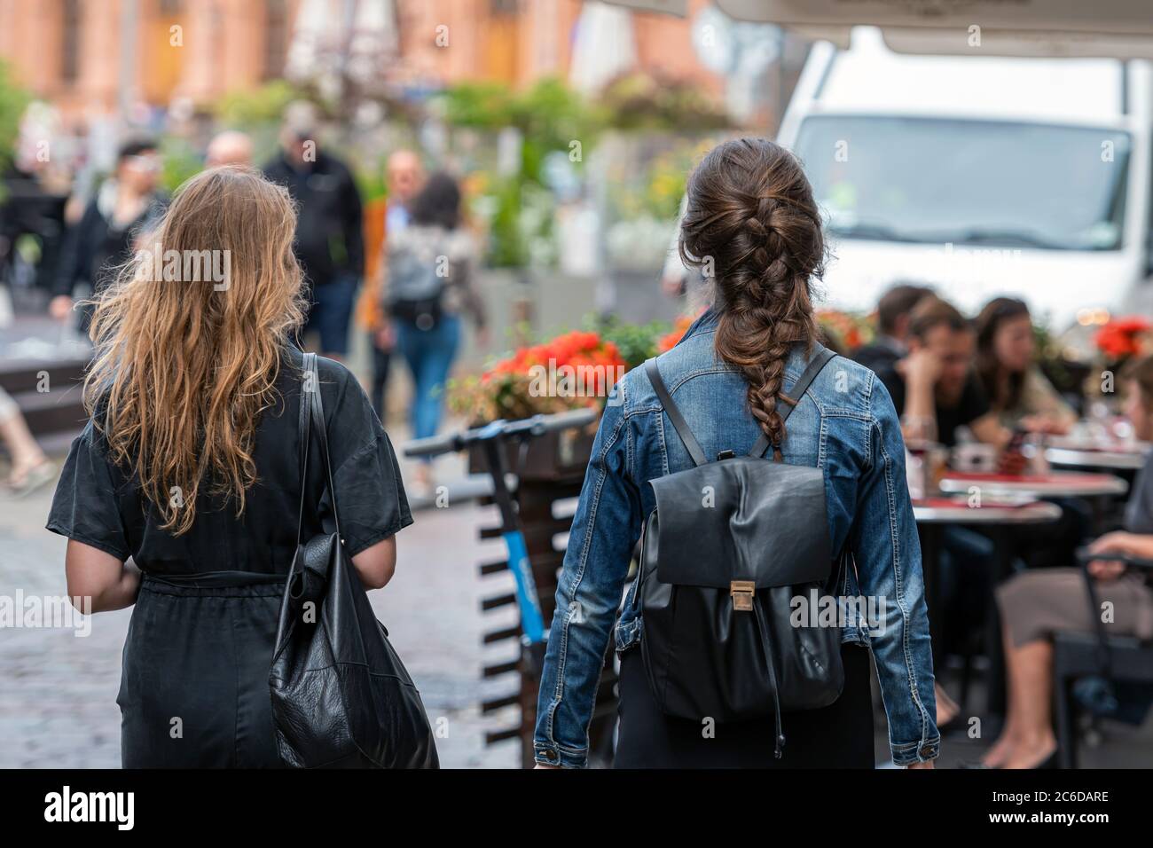 Riga, Lettland - 3. Juli 2020: Einheimische und Stadtgäste genießen einen warmen Sommertag auf dem Rigaer Altstädter Rathausplatz, im Vordergrund zwei Frauen von hinten Stockfoto